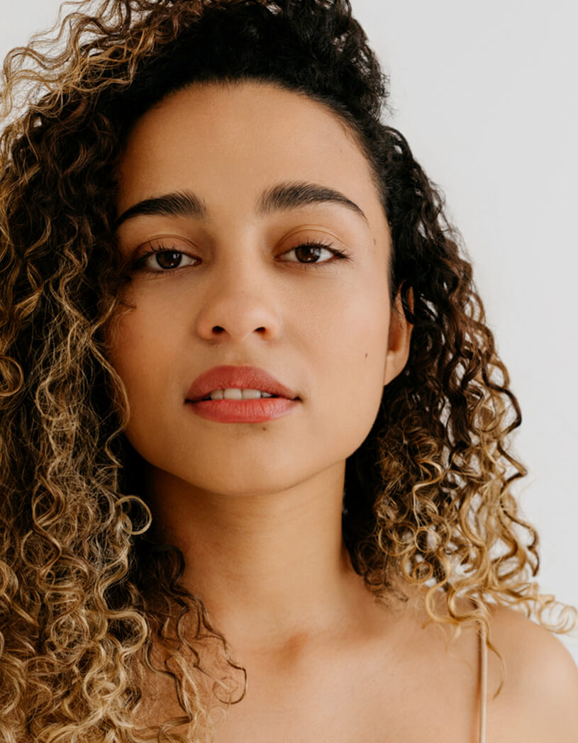 Model with curly hair and full, thick brows